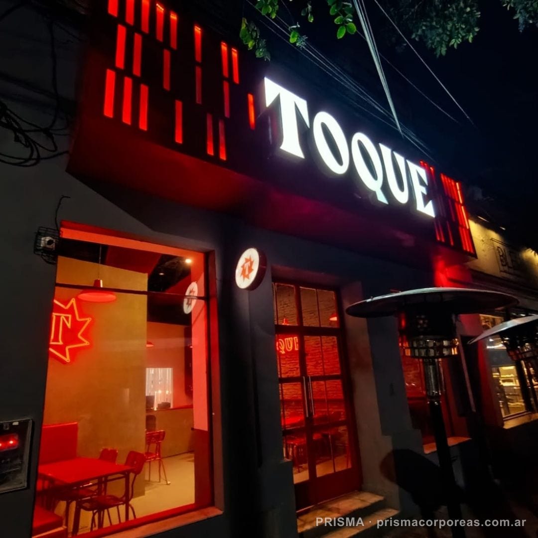 Letras corpóreas Toque con iluminación frontal de noche en fachada de local